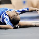 A female gymnast arching back on a mat